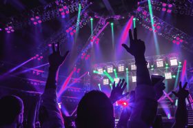 Rock concert, people with raised up hands dancing and enjoying loud music, having fun in night club, with pleasure spending time on musicl festival